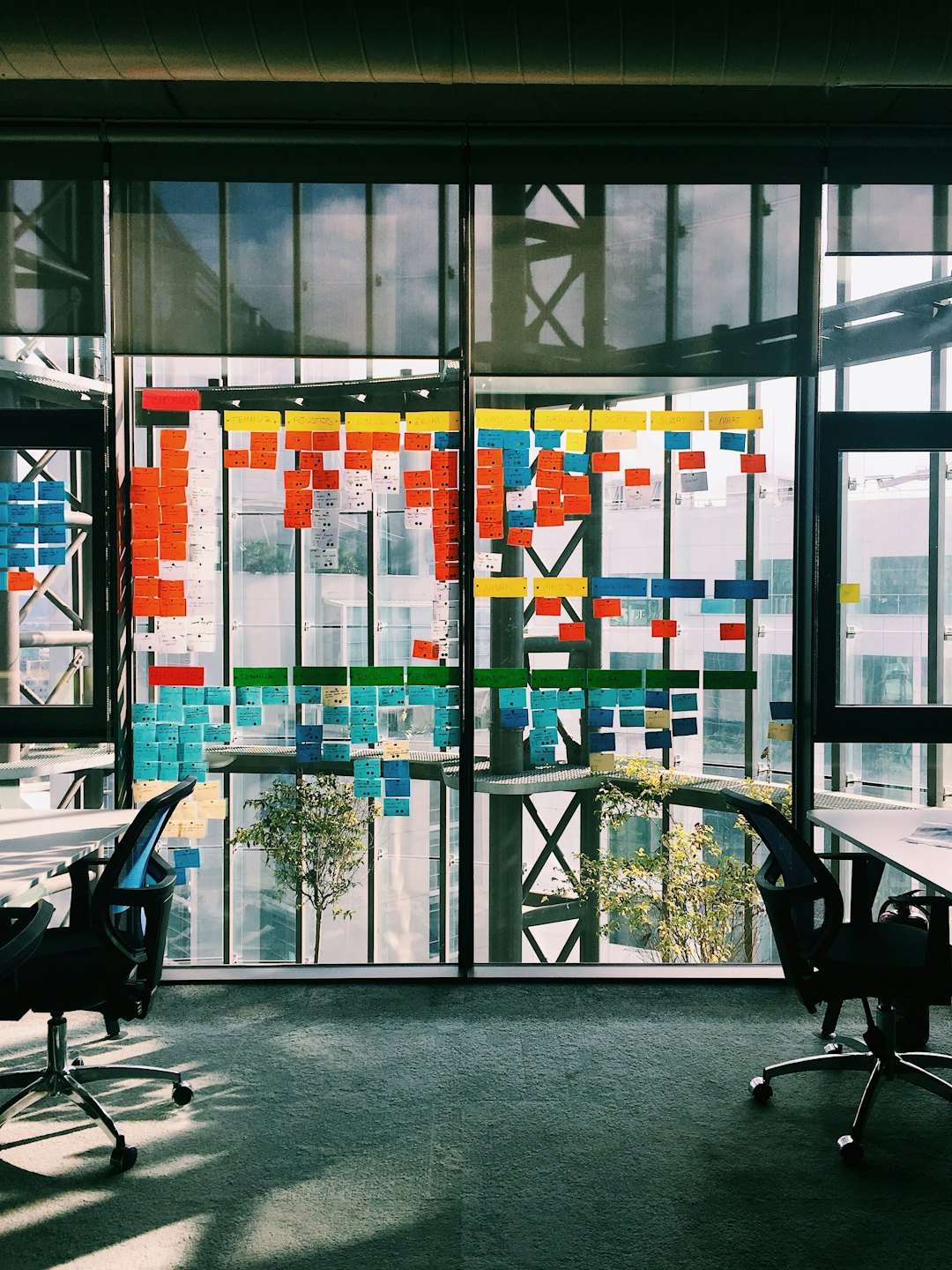 Glass wall covered with colorful sticky notes in a modern office.