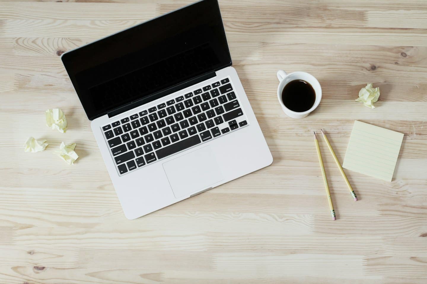 Organized desk with open laptop, coffee, and yellow supplies.